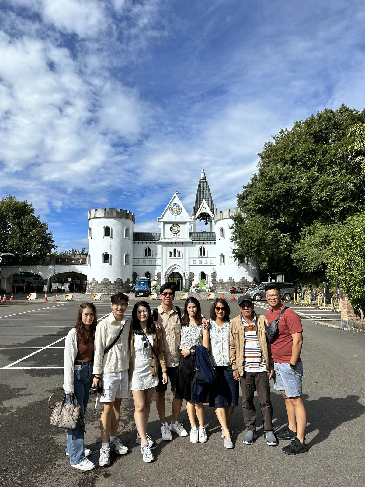 旅客在白色城堡式景點入口前合影